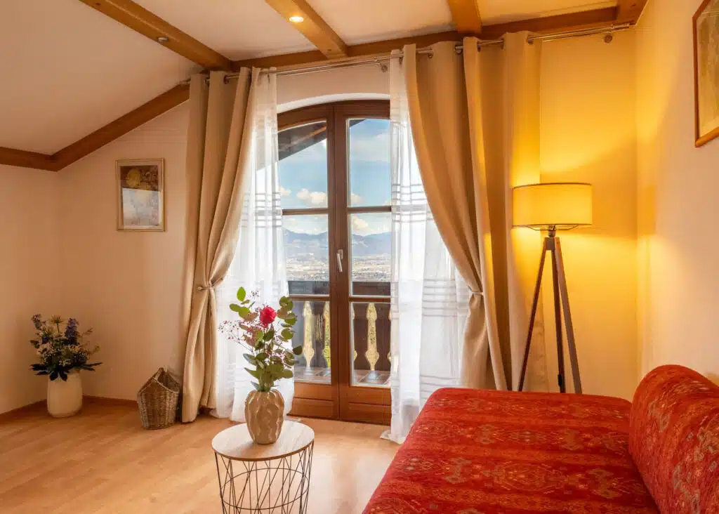 Gemütliches Wohnzimmer mit geschwungenem Holz-Balkontürfenster und Bergblick