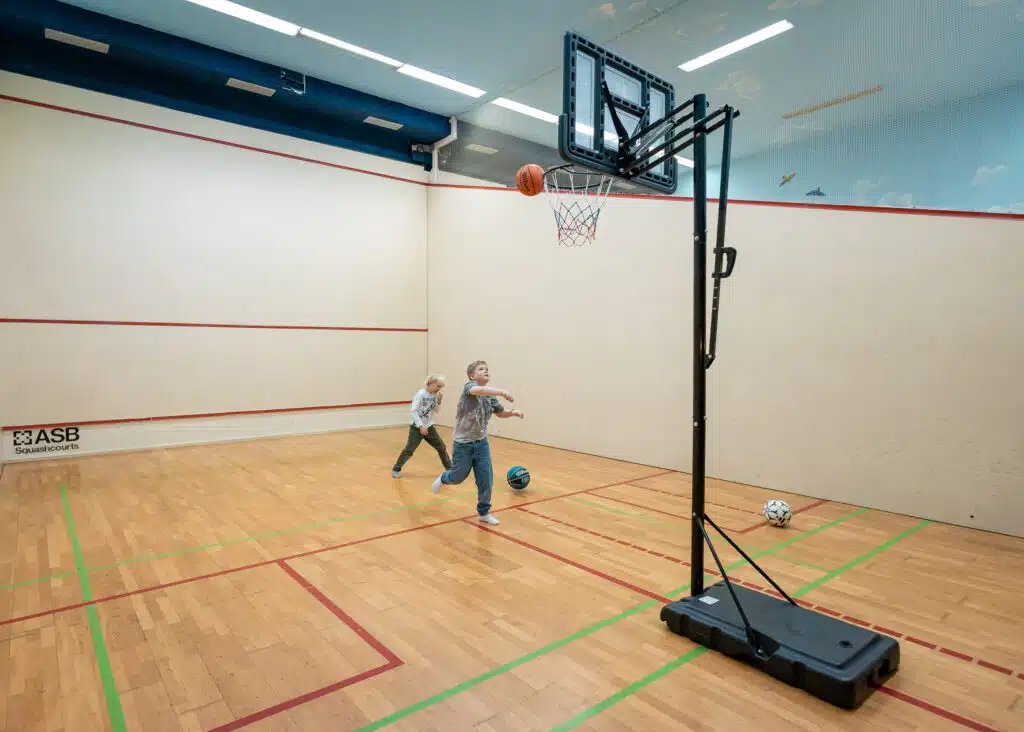 Zwei Jungen in einer Squash-Halle spielen Basketball